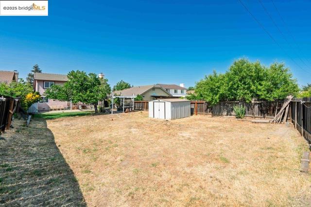 Fenced backyard featuring a storage unit