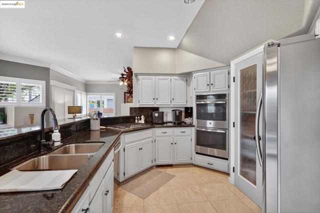 Kitchen featuring appliances with stainless steel finishes, light tile patterned floors, white cabinetry, recessed lighting, and dark stone counters