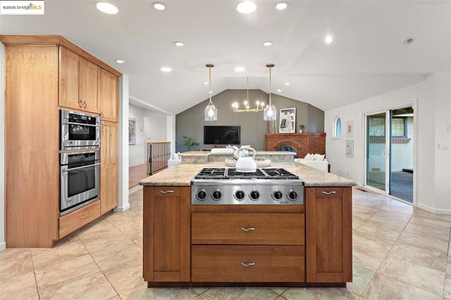 Kitchen featuring pendant lighting, stainless steel appliances, a kitchen island, recessed lighting, and vaulted ceiling