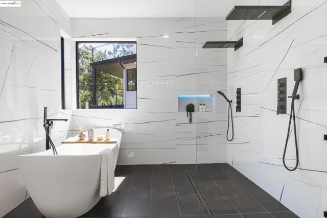 Bathroom featuring a freestanding bath, a marble finish shower, and tile walls