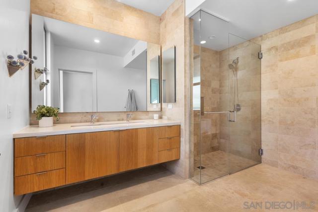 Luxurious primary en suite bath features a dual vanity with Macaubus quartzite granite countertops and Shinnoki sustainable custom wood cabinetry. Spacious shower includes Turkish stone tiles.