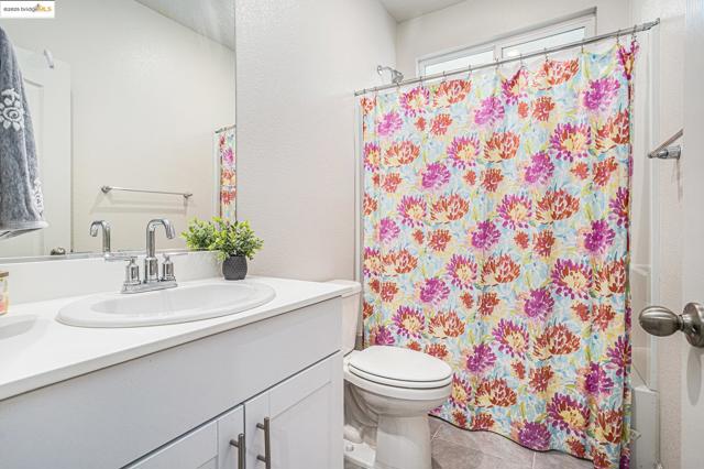 Full bathroom with vanity, shower / tub combo with curtain, tile patterned floors, and a textured wall