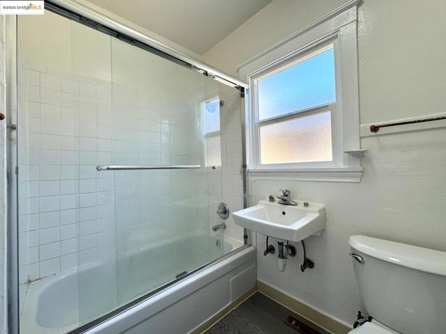 Bathroom featuring combined bath / shower with glass door and toilet