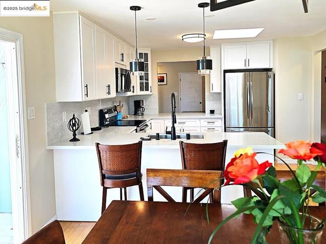 Kitchen featuring glass insert cabinets, tasteful backsplash, white cabinets, and stainless steel appliances
