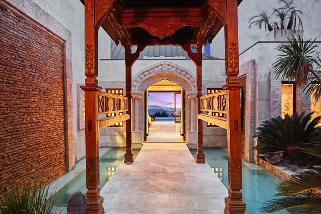 1446 Donhill Drive Beverly Hills, California This modern day oasis highlights Balinese architecture with custom features made with imported materials from all over the world. Enter through the front gate and step across a Jerusalem stone bridge above water and lush greenery to reach the main entrance of this architectural tour-de-force. Throughout the estate, floor-to-ceiling glass doors showcase the home's jetliner views. The open concept living room leads into a dining area adjacent to the kitchen. Three of the home's six bedrooms are private suites. The master suite features a private, spacious deck overlooking the city, his-and-hers oversized, walk-in closets, bathrooms and a two-sided fireplace. Additional highlights include a wine cellar, luxurious movie theater and gym. The zen characteristics of the estate flow through the serene backyard. Facing unobstructed city views, the backyard features a waterfall, statue of Buddha and a custom gazebo that stands above an infinity pool and spa. Located minutes away from the heart of Beverly Hills, this contemporary, Balinese-inspired estate offers secluded, luxurious living!