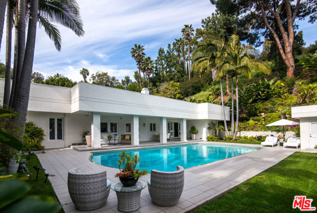 A meticulous gem in prime Beverly Hills, the timeless art deco design of exceptional scale sits on over half an acre of, privately- hedged and gated, lush landscaping. Grand 14ft ceilings, rooms lit with glass french doors and skylights, sleek lines, and exquisite finishings are all complemented by contemporary detail giving nods to the architectural attention.Top-of-the-line stainless steel appliances, oversized kitchen island, custom cabinetry, a breakfast nook, an open floor plan to a dining room, and a decadent custom wet bar just steps from the pool patio, all open to the backyard oasis for a luxurious dream for hosting large gatherings or intimate dinners alike. The primary suite features stunning french doors, a marble fireplace, dual closets, and dual spa-like bathrooms complete with a tub and steam shower. Three additional bedrooms, each offering natural light and elegant finishings for a warm and inviting atmosphere, a lounge area, and a separate staircase entry point complete the upper level.A secluded sanctuary, the grounds are beautifully programmed offering a pool, spa, natural waterfall, mature palm trees, and multiple seating areas. This gorgeous San Ysidro masterpiece is all on one of the most desirable streets in the prestigious Beverly Hills.