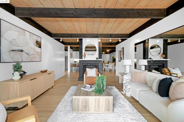 Living room with a fireplace, light wood finished floors, and a wooden ceiling with exposed beams