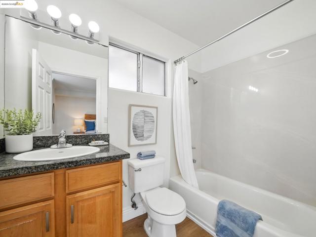 Full bath featuring shower / bath combo with shower curtain, vanity, and wood finished floors