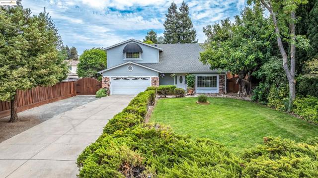 Traditional-style house featuring a shingled roof, driveway, a gate, stone siding, and a garage
