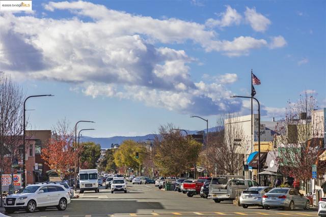 View of asphalt road featuring traffic lights, street lights, a mountain view, traffic signs, and curbs