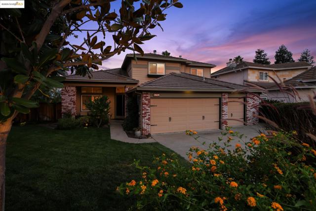 View of front of home featuring an attached garage, brick siding, a tile roof, and concrete driveway