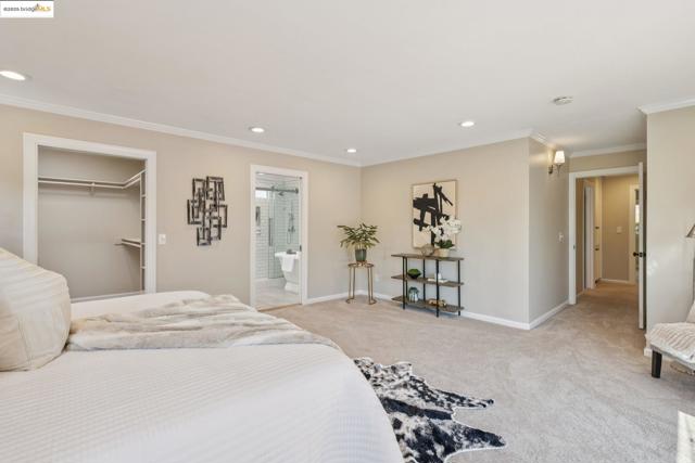 Bedroom with crown molding, light colored carpet, recessed lighting, connected bathroom, and a walk in closet