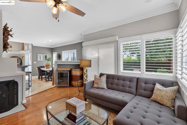 Living area with a fireplace with flush hearth, ornamental molding, light wood-style floors, a ceiling fan, and recessed lighting