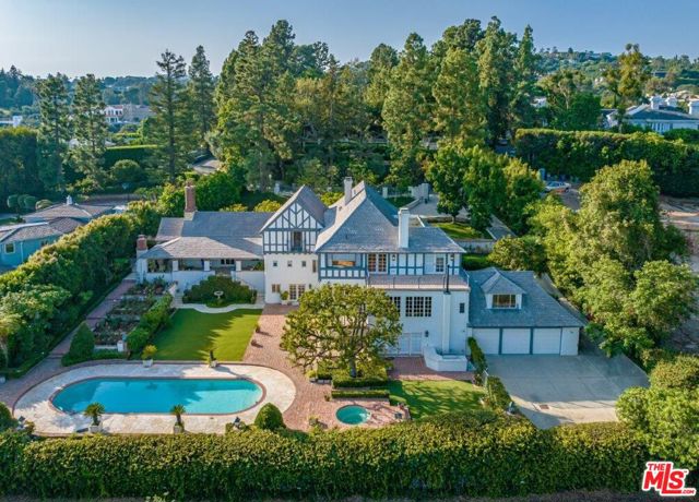 Nestled upon a cul-de-sac in the prestigious enclave of lower Bel-Air, overseeing awe-inspiring panoramas of the Bel-Air Country Club Golf Course, stands 543 Perugia. Double gates and a winding drive lead into this 9,615sf, three-story, elegant work of Tudor craftmanship, offering 5 bedrooms, 5 bathrooms and 2 power rooms. The expansive motor court, framed by towering trees and lush foliage, provides a serene, inviting entrance. Enter the grand foyer, seamlessly connecting to the formal living room, replete with a dramatic stone fireplace, exposed wood beam ceiling and generous covered terrace showcasing Bel-Air Country Club golf course fairway views and beyond. The elegant formal dining room with architectural crown molding and discreetly concealed storage paneled walls effortlessly flows into a secluded terrace and garden area. The bright chef's kitchen features an adjoining breakfast area, oversized island, walk-in pantry and butler's pantry. The exceptional entertainment lounge, generously proportioned to accommodate gatherings of distinction, boasts a grand wood fireplace, speakeasy-style hidden wet bar, custom shelving and original wood flooring, all enveloped by walls of windows and a terrace that frames the land and cityscape views. An adjacent art studio or bonus room offers an idyllic retreat for creativity and inspiration. Ascend the stairs to the second floor, where the light-filled primary suite awaits, featuring a striking wood and marble fireplace, vast terrace with scenic beauty and bathroom suite complete with sauna, soaking tub, standup shower/bathtub and spacious walk-in closet. An open area on the landing provides a versatile space for an office/den. An additional guest bedroom suite completes this floor. The lower level of the residence encompasses three more bedroom suites, a three-car garage, utility room, recreation room with wet bar and fireplace and a covered terrace. An elevator discreetly serves all floors. The romantic meticulously landscaped grounds offer a swimming pool and spa, outdoor BBQ area, rose garden and ample parking. Thoughtfully designed for private hosting and entertaining, this prime Bel-Air estate presents enticing opportunities for customization and modernization to bring your unique vision to life.