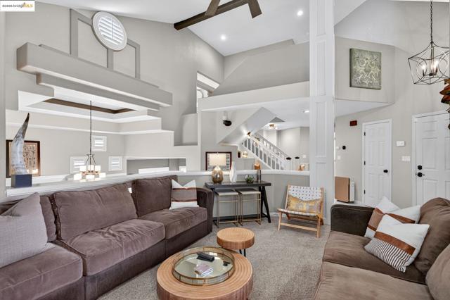 Living area featuring a chandelier, carpet flooring, stairway, high vaulted ceiling, and beam ceiling