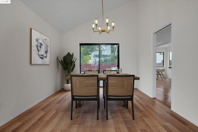 Dining space with wood finished floors, a chandelier, and high vaulted ceiling