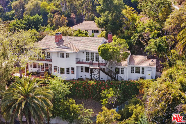 Create an exquisite home on a wooded acre lot in the Palisades Riviera. This respectable home and the full guest house can be expanded and remodeled into a significant estate. Or one could build a stunning new residence on the exceptional site. A long private drive leads to a grand courtyard bordered by tropical flowers. The current 5 BR home is a comfortable traditional style, surrounded by flowering trees and lush plantings. All rooms open to private patios and gardens. The entertainment rooms all have fireplaces. The large eat-in kitchen is filled with sunlight. Two bedroom suites plus office and powder room complete the main floor. The commodious primary bedroom has a newer bath and two closets. Two additional Jack and Jill bedrooms complete the second floor. The full guest house is a remarkable bonus. With a kitchenette, living and dining area and four additional rooms which could be offices or bedrooms. A rare opportunity and incredible value that demands attention.