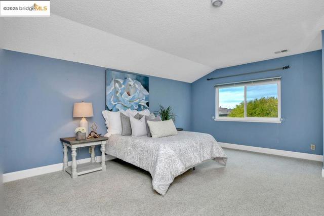 Bedroom featuring carpet flooring, vaulted ceiling, and a textured ceiling