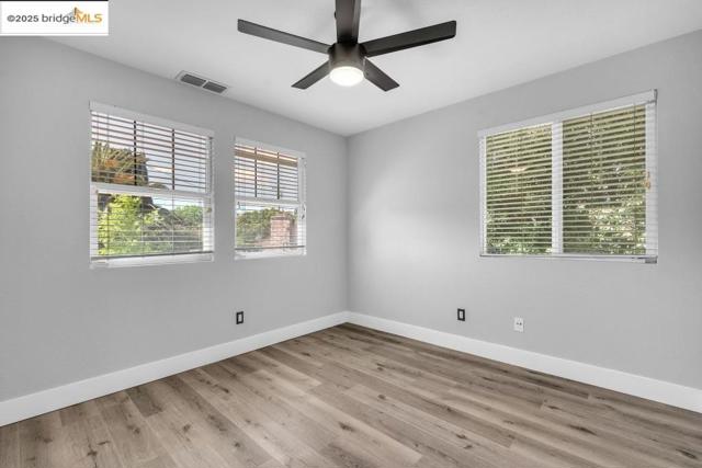 Spare room with plenty of natural light, wood finished floors, and a ceiling fan