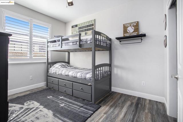 Bedroom 3 is adjacent to bedroom 2, with a ceiling fan, laminate wood-type flooring, and shutters for window covering.