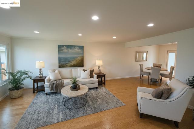 Living room with recessed lighting, light wood-style flooring, and ornamental molding