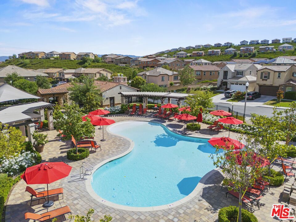 Welcome to this stunning, move-in ready 2-bedroom, 2-bathroom condo located in the highly sought-after Lamplight/Lantana enclave of the Five Point Valencia community. This spacious second-floor corner unit offers 1,140 sqft of modern living with soaring ceilings, abundant natural light, and a private balcony perfect for relaxing or entertaining. The open-concept kitchen is equipped with high-end stainless steel appliances, including a French-door LG refrigerator, GE Profile 5-burner gas range with convection oven, GE Profile microwave, and ultra-quiet GE Profile dishwasher. Elegant white cabinetry, granite countertops, and a designer tile backsplash complete the stylish space. Additional features include two spacious bedrooms, two full bathrooms, in-unit LG ThinQ washer and dryer, Hunter Douglas smart window shades, recessed lighting, leased solar panels, a 1-car private garage, and an exterior storage closet. Enjoy resort-style community amenities including three pools, a clubhouse, fire pit, community garden, walking trails, picnic areas, and dog-friendly spaces. Conveniently located near award-winning schools, Westfield Valencia Mall, Six Flags Magic Mountain, golf courses, and the I-5 freeway. This beautifully maintained home offers luxury, convenience, and comfort in one of Valencia's premier communities. Don't miss it!