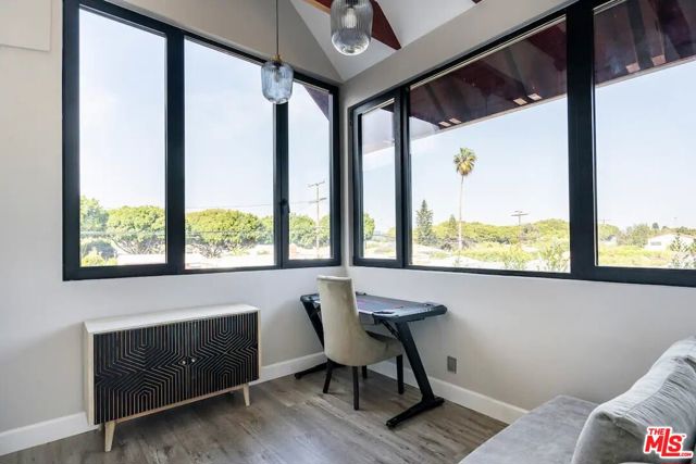 This gorgeous sunroom has a seating area, work space, and cabinet space