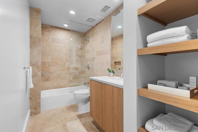 Luxurious guest bathroom features a single vanity with Macaubus quartzite granite countertops and Shinnoki sustainable custom wood built in cabinetry. Spacious shower includes Turkish stone tiles, as well as a tub.