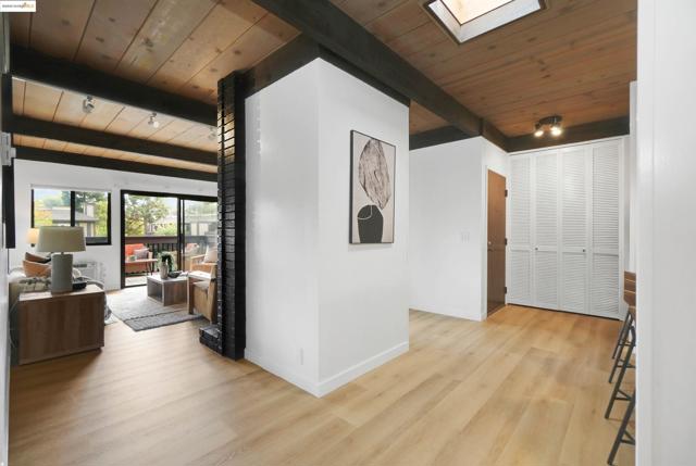 Hallway with a wood ceiling with exposed beams, light wood-style floors, and a skylight