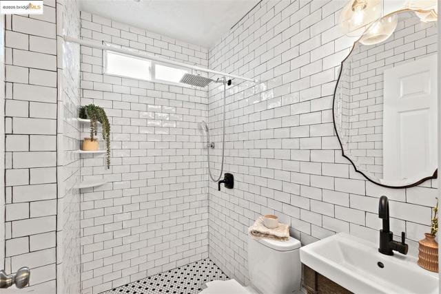 Bathroom featuring a shower stall and tile walls