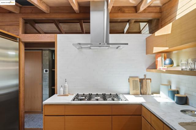 Kitchen with open shelves, island exhaust hood, tasteful backsplash, stainless steel appliances, and modern cabinets
