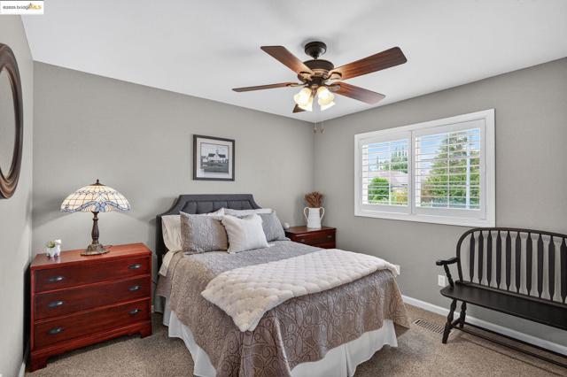 Carpeted bedroom featuring ceiling fan and baseboards