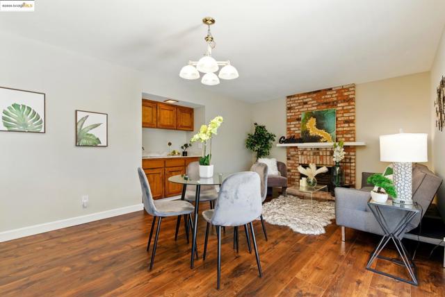 Dining area with a chandelier, dark wood-style floors, and a brick fireplace
