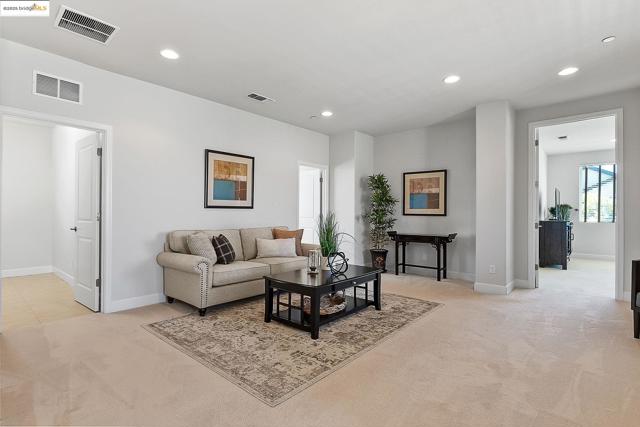 Living area with light carpet and recessed lighting