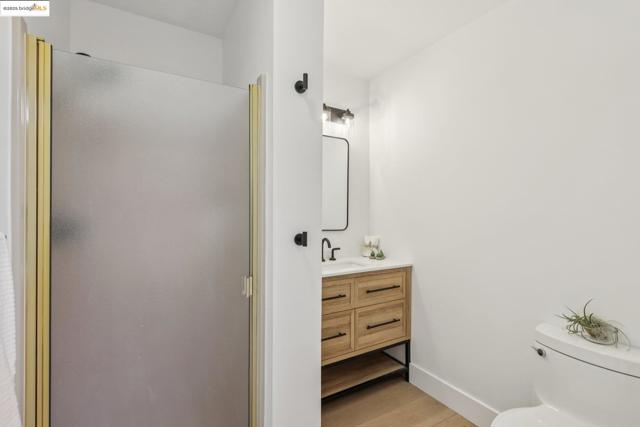 Full bath featuring vanity, wood finished floors, and a stall shower