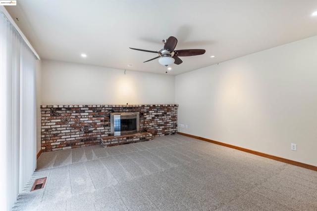 Unfurnished living room featuring carpet floors, a brick fireplace, a ceiling fan, and recessed lighting
