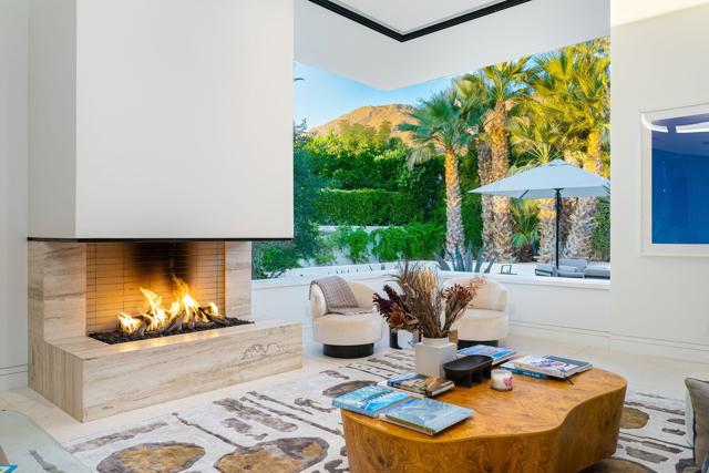 Located just a couple of blocks from Palm Springs' downtown shops and Uptown Design District in the highly sought after Movie Colony, this furnished stunning contemporary showplace has been eagerly awaited by discerning buyers and is expected to sell quickly. Crafted in 2020, the gated estate coyly blends modern and Mid-Century Modern architectural styles into a one-of-a-kind masterpiece that extends approx. 4,202 s.f. on one level. Stylish double doors open to an impressive foyer that boasts an atrium with in-ground fountain and illuminating skylight. MCM-inspired interior screens add intrigue to the living room, where a floating fireplace, 14' ceiling and clerestory windows are showcased. Numerous sets of slideaway glass pocket doors and windows eraseborders in the home, which hosts 4 ensuite bedrooms and 4.5 baths, including a casita with separate entrance. A formal dining room provides atrium views and the ideal setting for entertaining, while the custom kitchen opens to an indoor/outdoor bar and displays a dual-waterfall island, leathered-marble countertops, a large walk-in pantry and more. Grounds reveal mountain views, large patios for entertaining, custom lighting, a built-in BBQ, an open-air fireplace with built-in seating, and a limestone-finished pool with spa and tanning shelf.