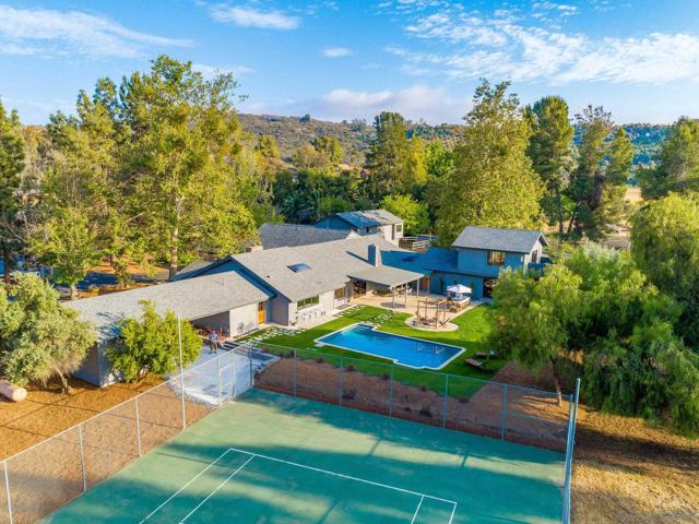 This stunning estate offers resort-style living with a sparkling pool, spacious outdoor areas, and a tennis court easily set up for pickleball. Perfect for family retreats or high-end rentals.