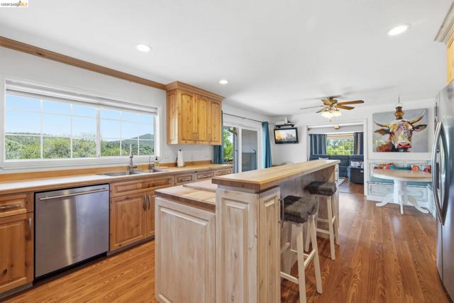 Spacious kitchen featuring natural wood cabinetry, wood-finish flooring, recessed lighting, and a stainless steel dishwasher