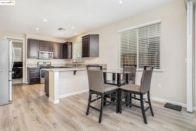 Kitchen featuring dark brown cabinets, stainless steel appliances, light stone counters, recessed lighting, and a peninsula