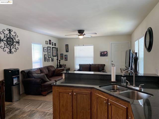 Kitchen featuring open floor plan, wood finished floors, brown cabinetry, and dark countertops