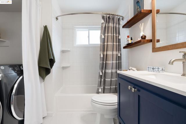 Full bathroom featuring washer / dryer, shower / bath combo, vanity, and light tile patterned floors