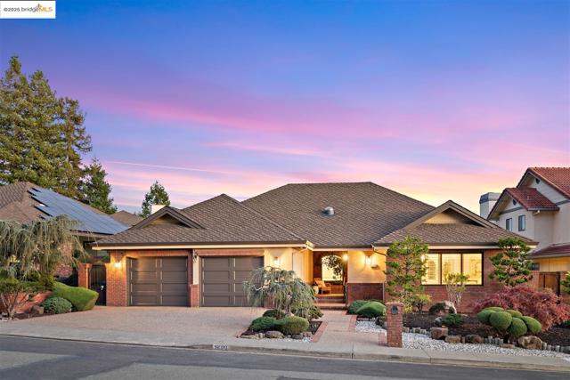 View of front of property with decorative driveway, a garage, brick siding, and a shingled roof