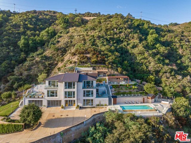 Nestled atop a picturesque hill, this extraordinary architectural estate sprawls over 7 acres and boasts breathtaking views from every window. With 5 bedrooms and 6.5 bathrooms, this Malibu retreat seamlessly blends luxury, and privacy, just a short drive from the beach. This custom-built 6,406 square foot home, with an additional 600 square foot bonus area, is a testament to indoor-outdoor California living. The residence features an infinity pool, soaring vaulted ceilings, oak engineered floors, expansive Pella windows, and a 3-story commercial elevator. Made for entertaining the home features a large chef's kitchen, equipped with top of the line Wolfe appliances, that opens up to the living room leading out to the approx. 3,500 square foot deck. The spacious 4-car garage offers limitless storage with built in cabinetry lining the back wall. Just beyond the property, you'll find yourself adjacent to miles of stunning hiking and biking trails. This home is the ultimate embodiment of luxury and tranquility, where every comfort and modern amenity has been thoughtfully considered.