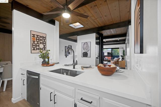 Kitchen with a wooden ceiling with exposed beams, white cabinets, light stone counters, a ceiling fan, and light wood-style flooring