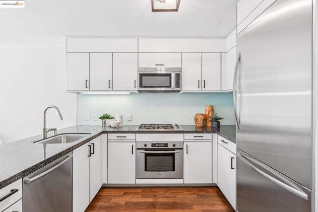 Kitchen with appliances with stainless steel finishes, dark wood-style flooring, white cabinets, dark stone countertops, and a peninsula