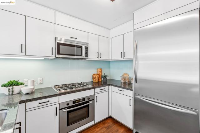 Kitchen featuring appliances with stainless steel finishes, white cabinets, dark wood-type flooring, and dark stone countertops