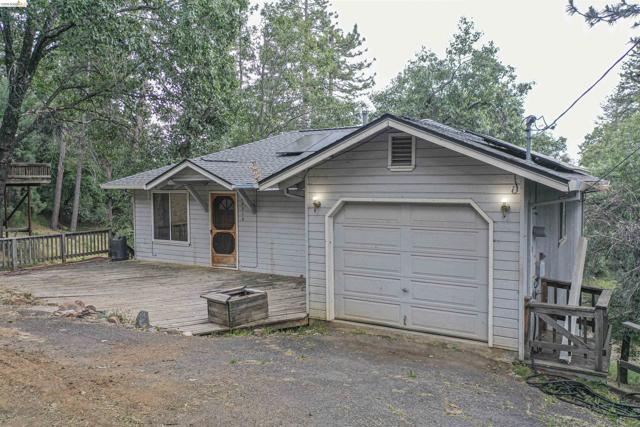 Siding exterior with a built-in garage, front deck, and surrounding mature trees