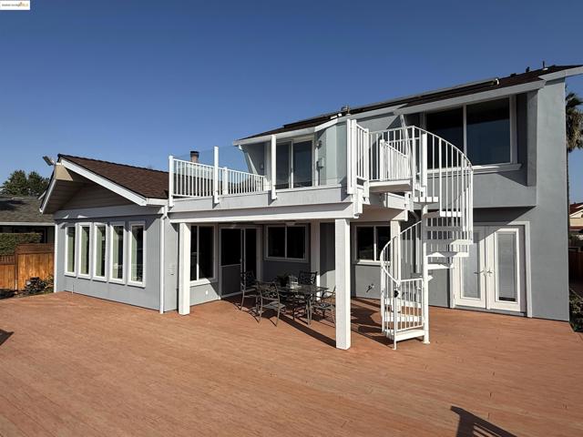 Back of house featuring a wooden deck, stucco siding, and a balcony