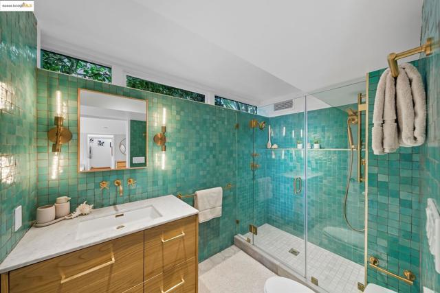 Bathroom with tile walls, vanity, a shower stall, and tasteful backsplash